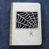wooden note book cover with a spider's web design